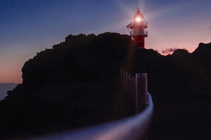 A lighthouse shining a light at dusk