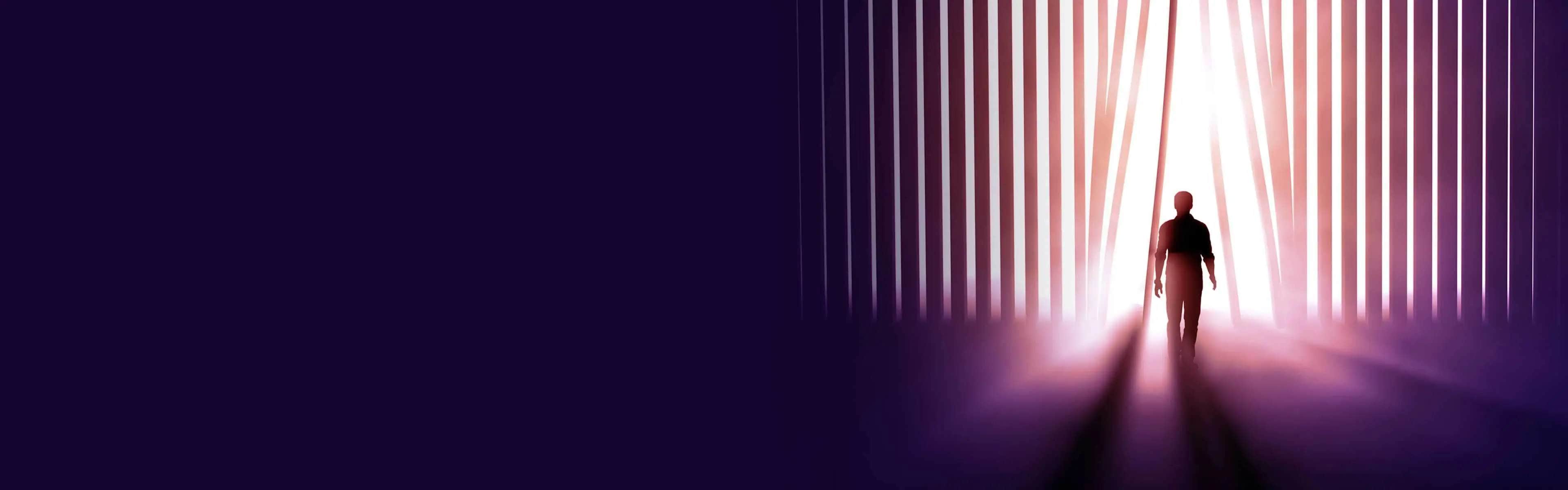 A silhouetted man walking toward a light.