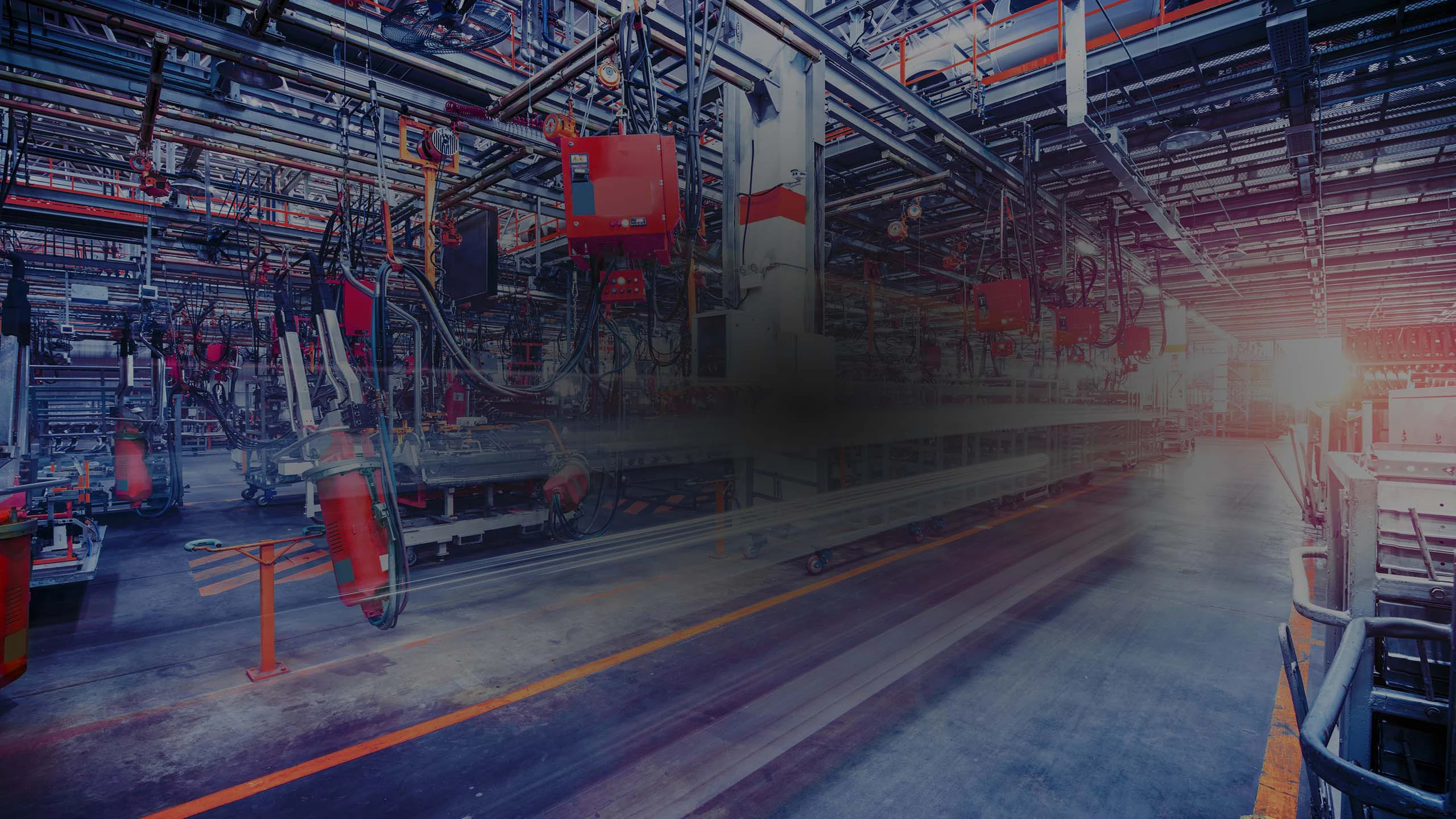An inside view of a manufacturing industry featuring heavy machines connected with robust wires, representing use of cutting-edge technology for enhanced efficiency.