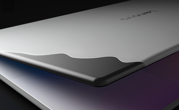 A Lenovo Googlebook 15 laptop, lid slightly open, with dozens of colorful graphic lines appearing to swoop underneath it.