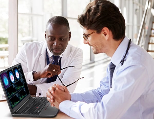Two medical professionals looking at Lenovo ThinkPad P16v (16” AMD) mobile workstation, showing a series of scans and charts on screen