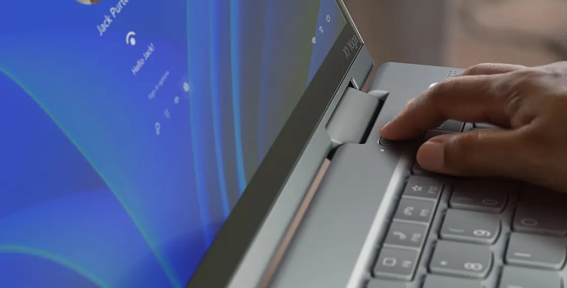 A finger shown activating the fingerprint reader integrated with the power button on the Lenovo ThinkPad X1 Yoga Gen 8 2-in-1 laptop.