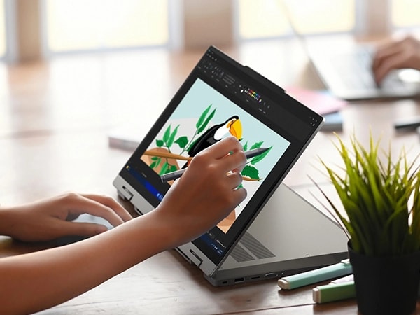 Front, right side view of Lenovo ThinkBook 14 2-in-1 Gen 4 (14” Intel) laptop in tablet mode with keyboard rotated at 180 degrees where a person is shown working on a coloring app using the Lenovo Slim Pen.