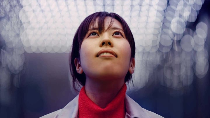 A woman wearing a white lab coat looking upwards