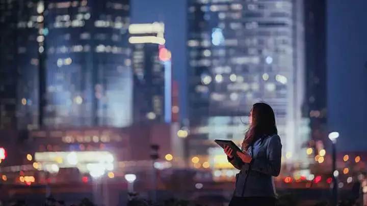 A woman holding a notebook and looking back at the city skyline