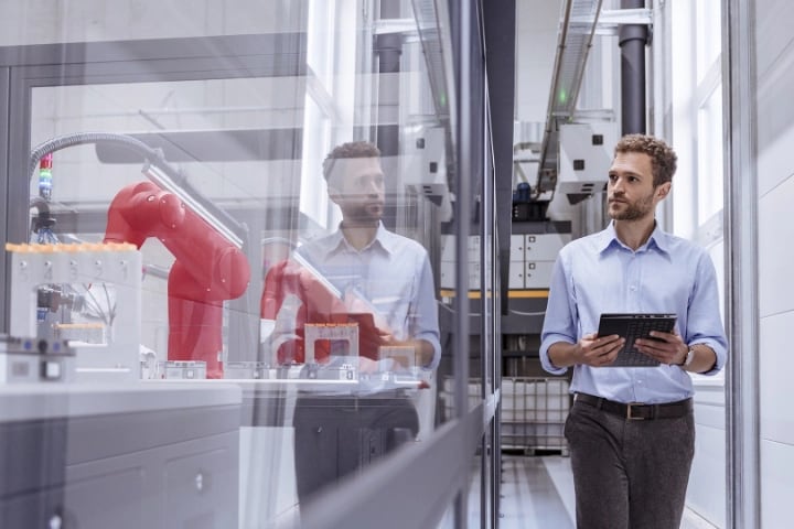 Hombre en una planta de fabricación de alta tecnología, cuya imagen se refleja en el vidrio