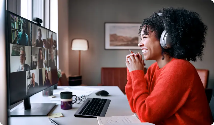 Woman in home office video conferences with colleagues on a Lenovo monitor. 