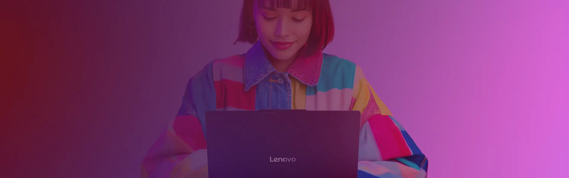 A woman in a multicolored shirt using a Lenovo laptop