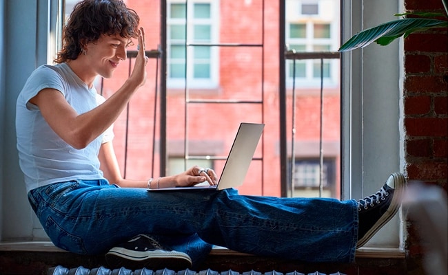 Assis sur le seuil de la fenêtre dans un environnement urbain, une personne fait fureur sur un portable Lenovo.