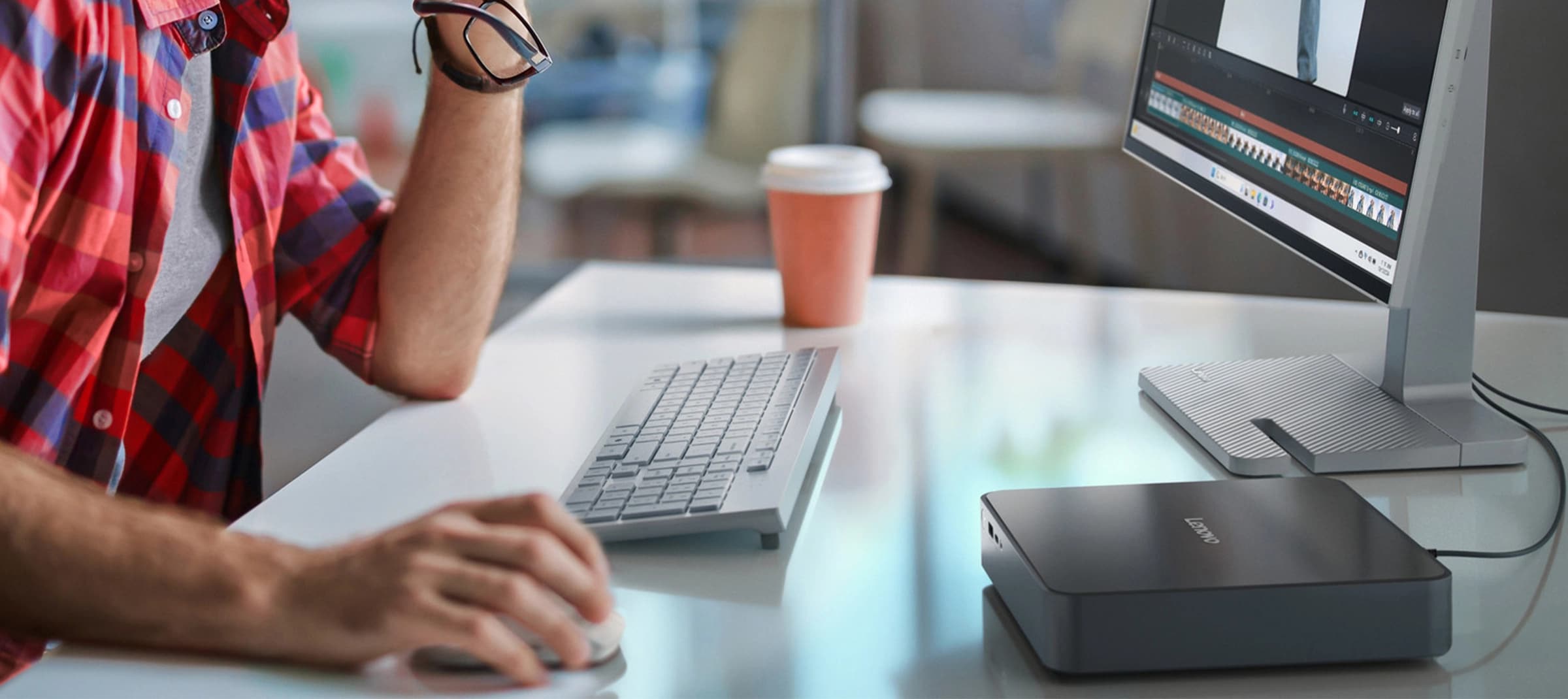 Avec un mini-ordinateur de bureau IdeaCentre au premier plan, une main d’homme utilise une souris à côté d’un clavier (en option) et devant un moniteur optionnel.