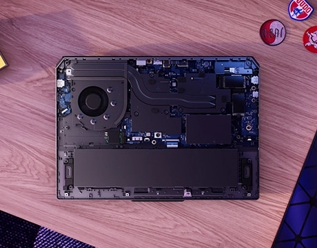 Lenovo LOQ Essential 15IRX11 gaming laptop on a desk – bottom view, with cover removed to reveal internal components.