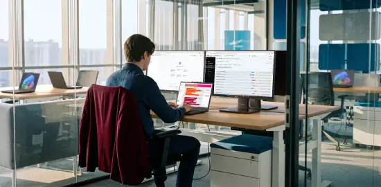 畫面一名男子使用連接雙顯示器的 ThinkPad，並運用 Lenovo 裝置編排功能進行預測性分析。