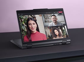 A convertible laptop in tent mode displaying a video call with three participants, set against a pink and black background, showcasing its flexible design ideal for remote collaboration.