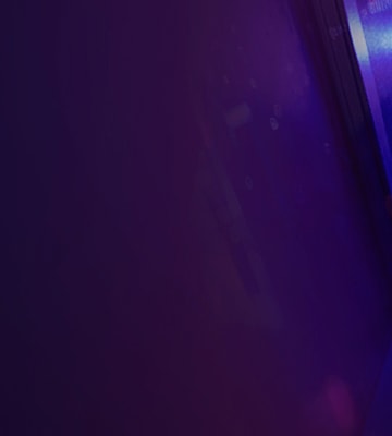 Person working inside a Lenovo server rack, adjusting hardware components under purple and blue ambient lighting.