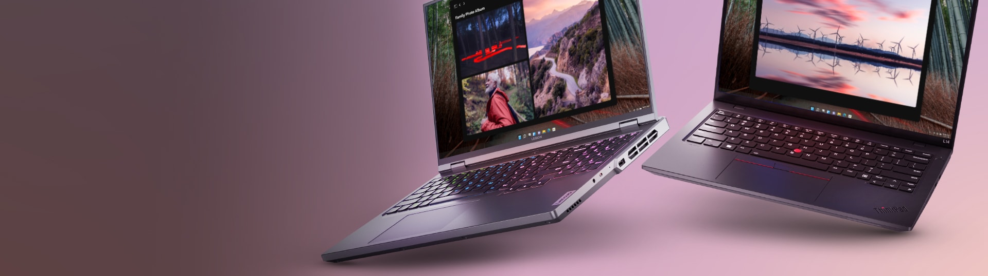 Two laptops are open and placed on a pink surface. The laptop on the left has a colorful display with a mountain scene, and the laptop on the right has a screen showing a reflection of trees and the sky at sunset.