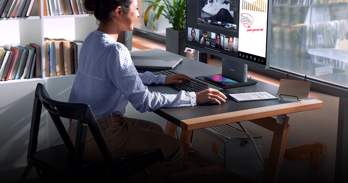 A women on a desk working with a ThinkCentre neo 50a gen 5 all-in-one desktop