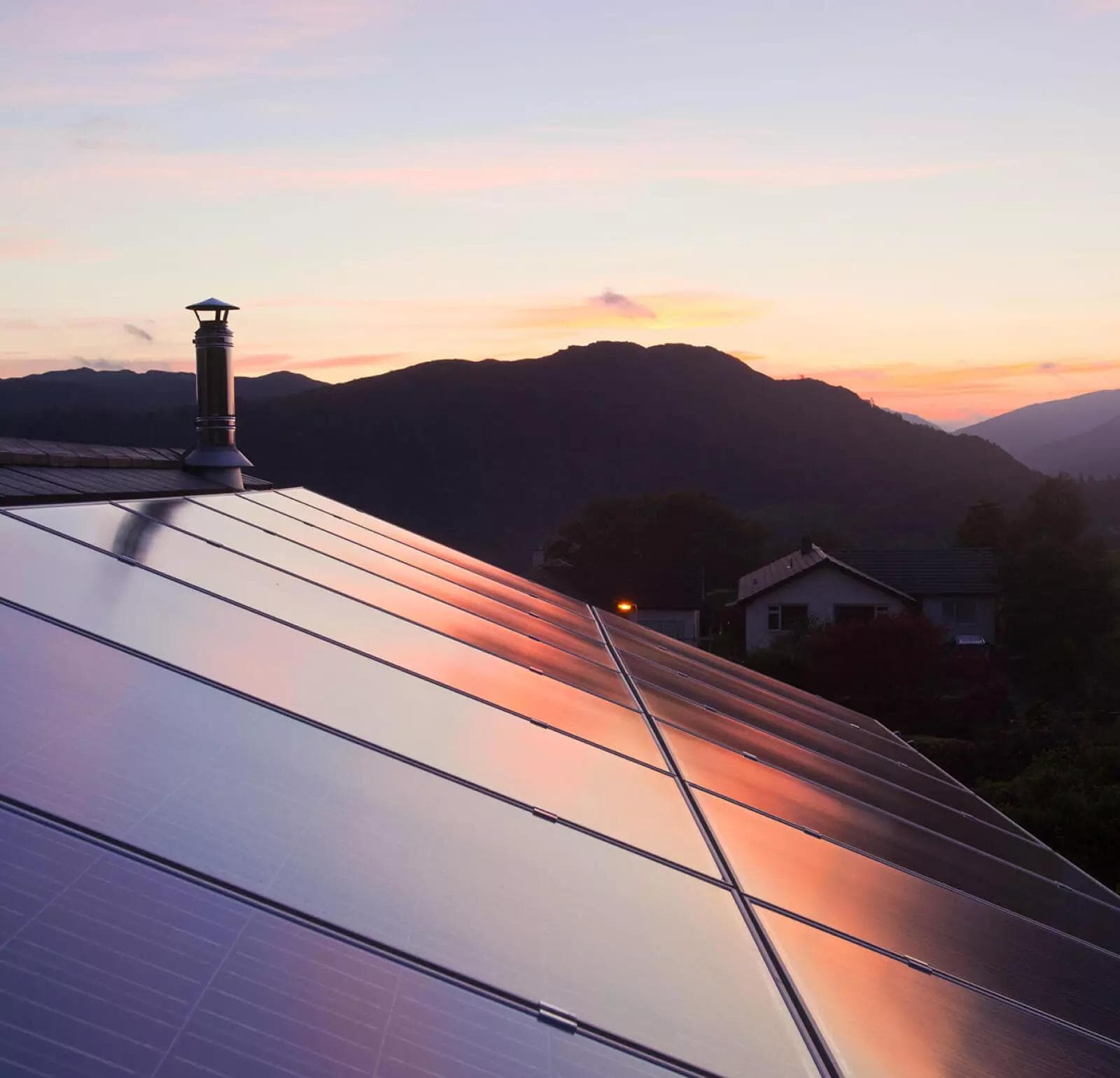Dům se solárními panely na střeše ve venkovském horském prostředí.