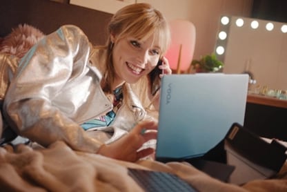 Smiling young person using Lenovo Yoga laptop.