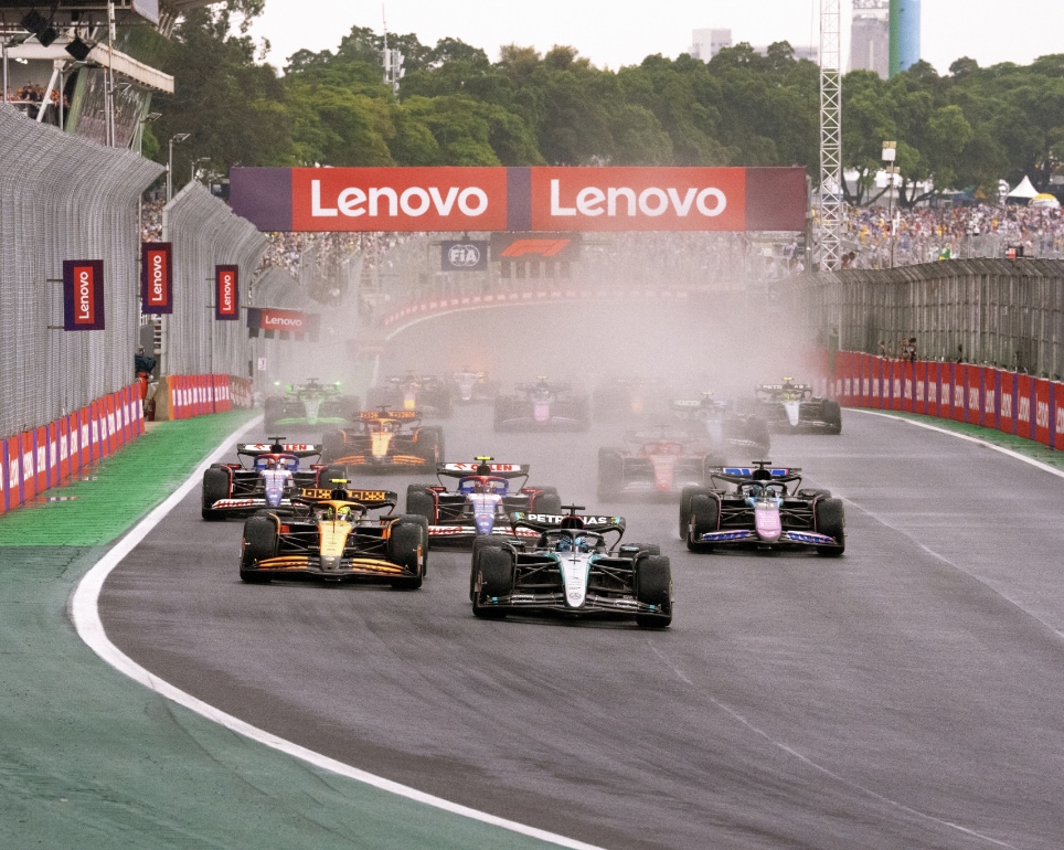 Un groupe de F1 sur une piste avec le logo de Lenovo en arrière-plan.