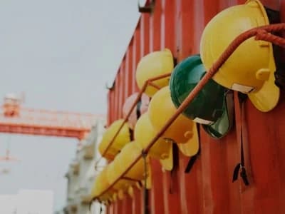 Row of hardhats neatly hanged on the side of a container