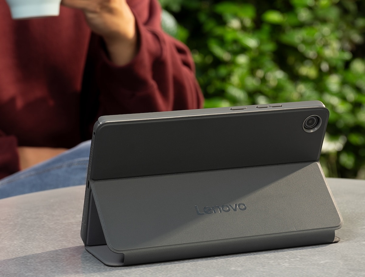 Tablette Lenovo avec étui protecteur folio garni sur une table dans un environnement extérieur.