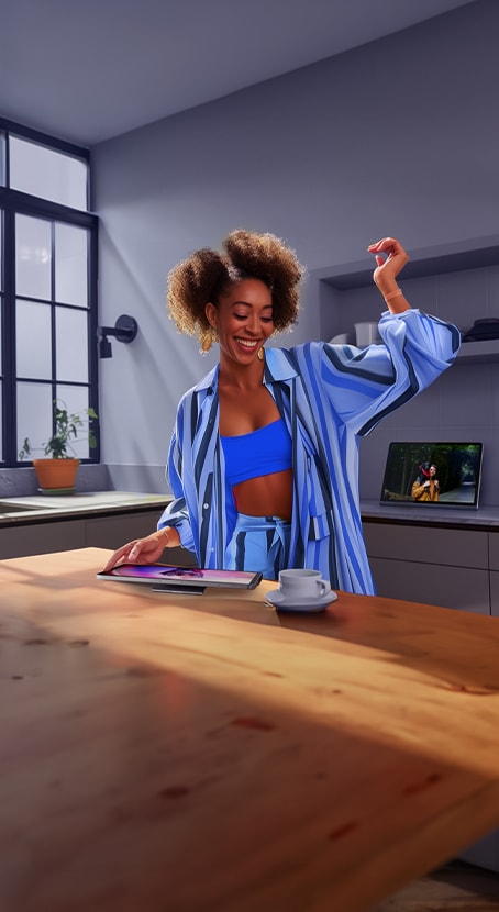 A womn dances joyfully while listening to music on her tablet.