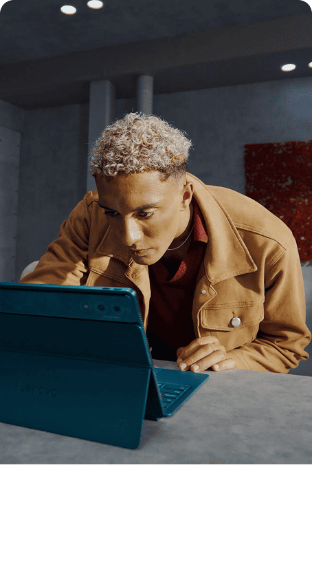 A man focuses intently while working on a Lenovo Yoga tablet at a desk in a modern interior.