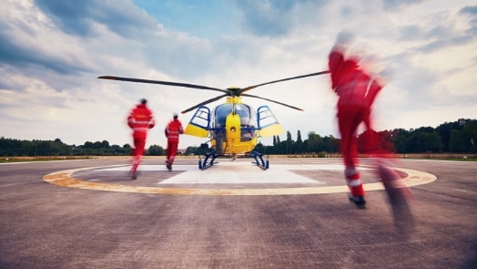 Medical helicopter on helipad with personnel in motion.