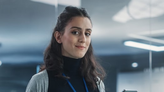 Young woman in business casual attire with a lanyard.