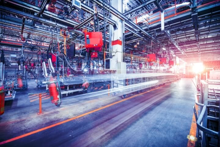 Man holding a tablet walking through a manufacturing plant.