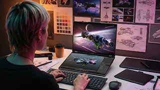 A person sits at a desk, using a wireless keyboard to work on a Lenovo Yoga Book Pro 3D 16″ laptop concept, which shows an illustrated spaceship on both displays.