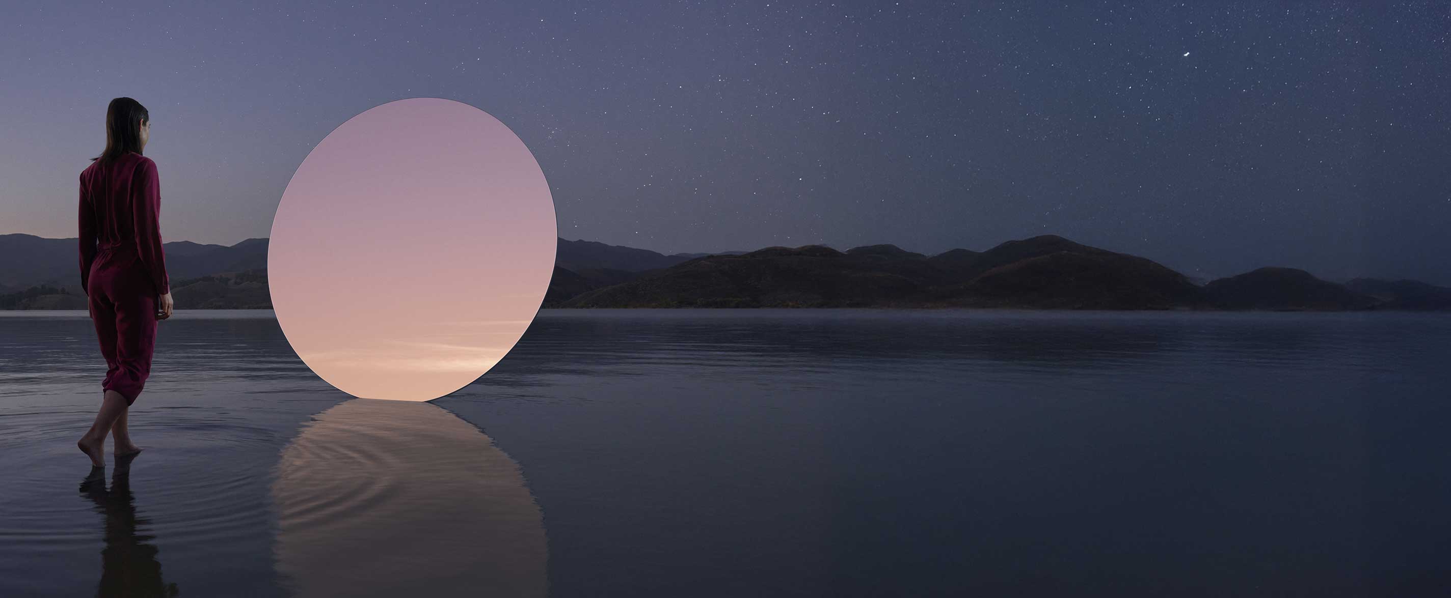 A woman walking on shallow water at dusk toward a circle.