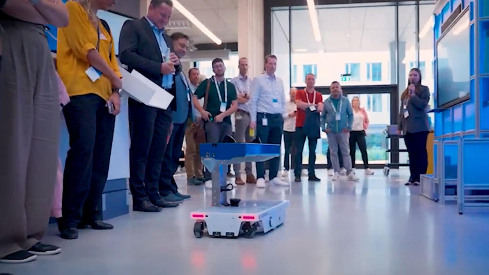 Colleagues watching a robot roll through the hallway