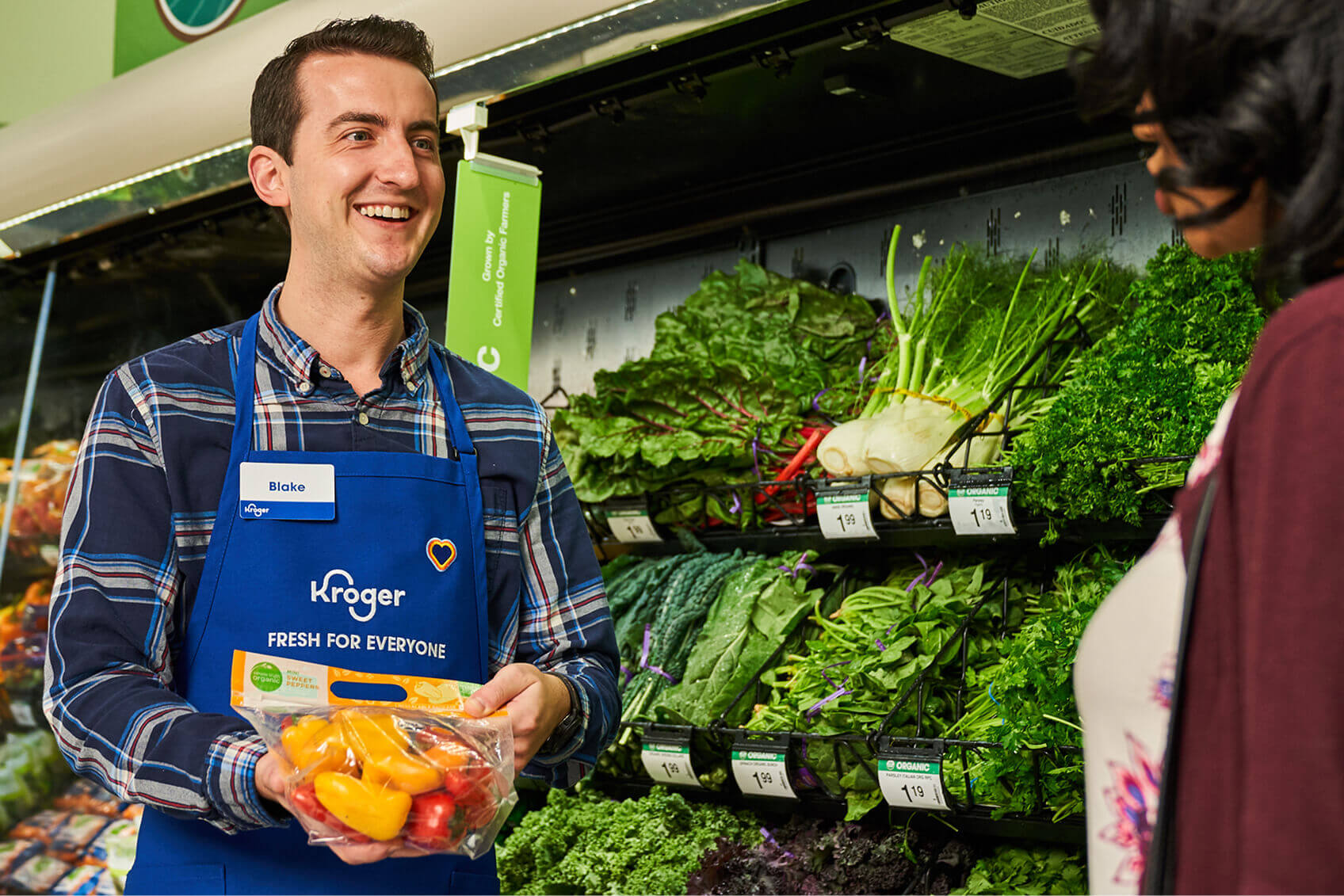 A Kroger employee helping a customer in the produce section.  