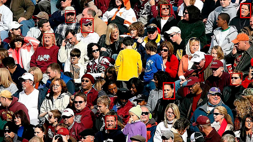 Eine Menschenmenge bei einer Sportveranstaltung mit roten Quadraten um die Gesichter einiger Fans. 