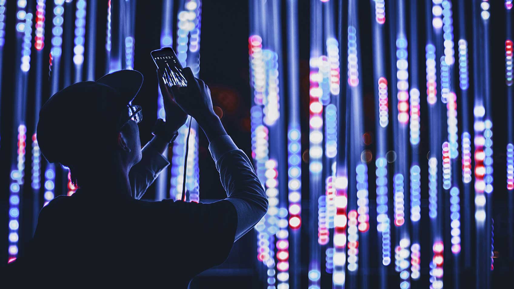 携帯電話をかざして青い光を撮影する男性。 