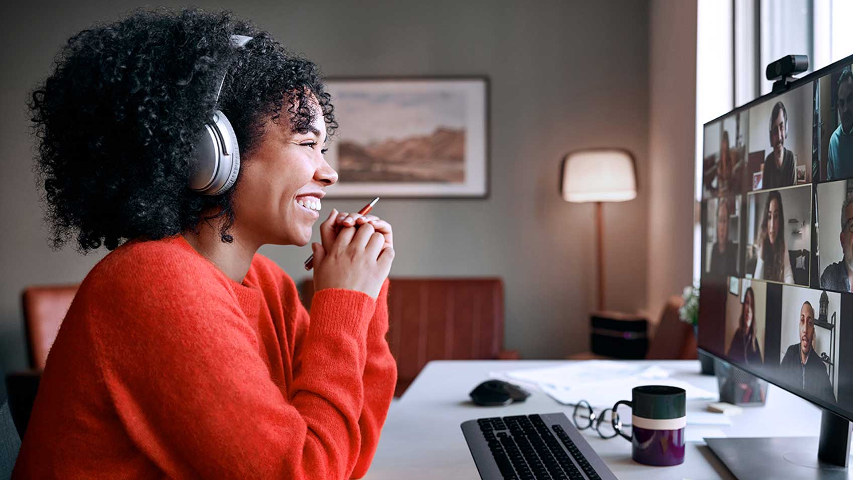 ヘッドセットを装着し、デスクに座って微笑む女性。