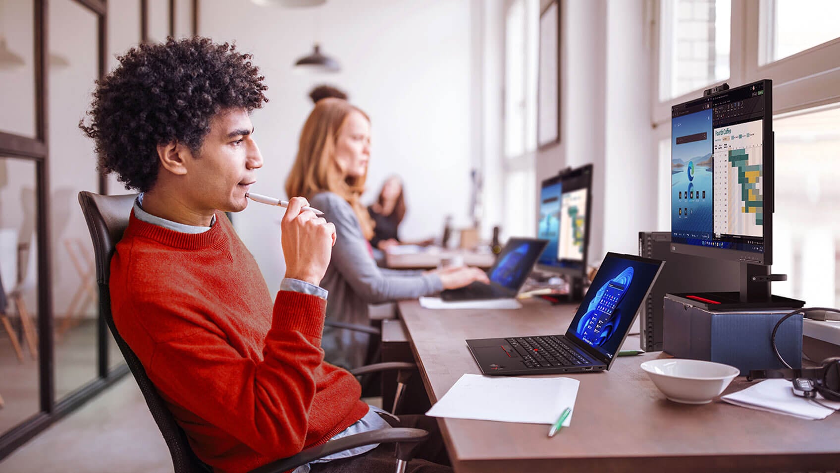 A row of people working on their laptops in an office