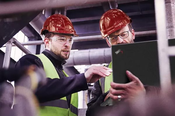 Two men in construction hats using a ThinkPad