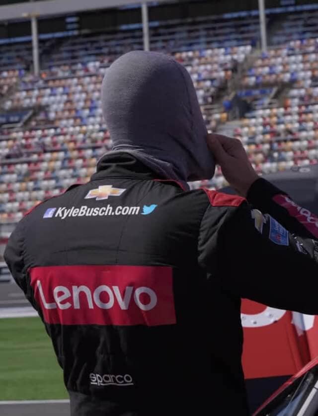 Image of a race car driver with a Lenovo logo on the back of his racing suit. 