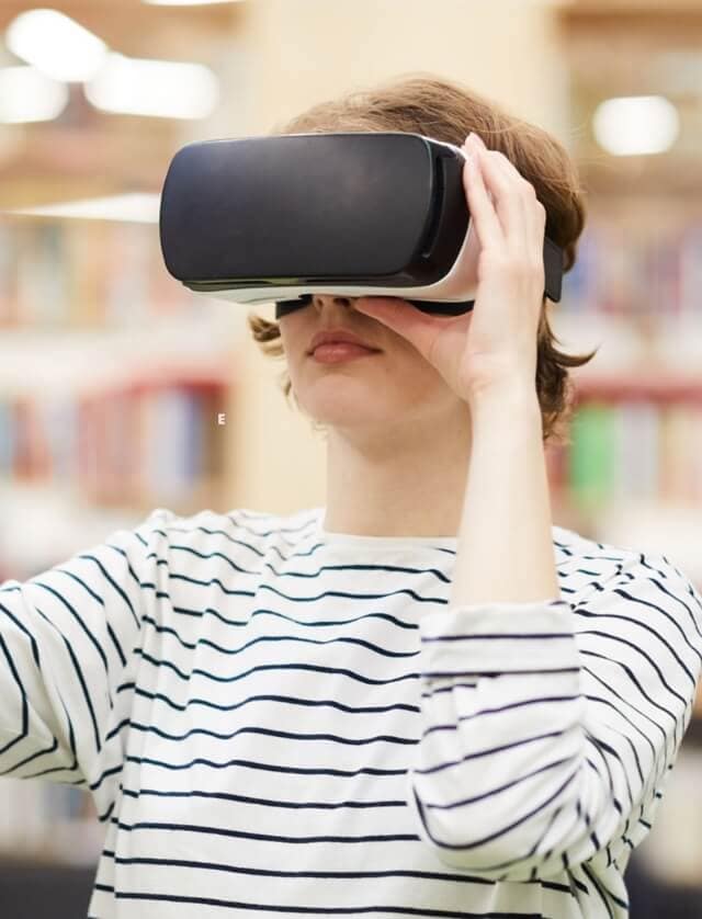 Picture of a woman wearing a virtual reality headset on her face.  