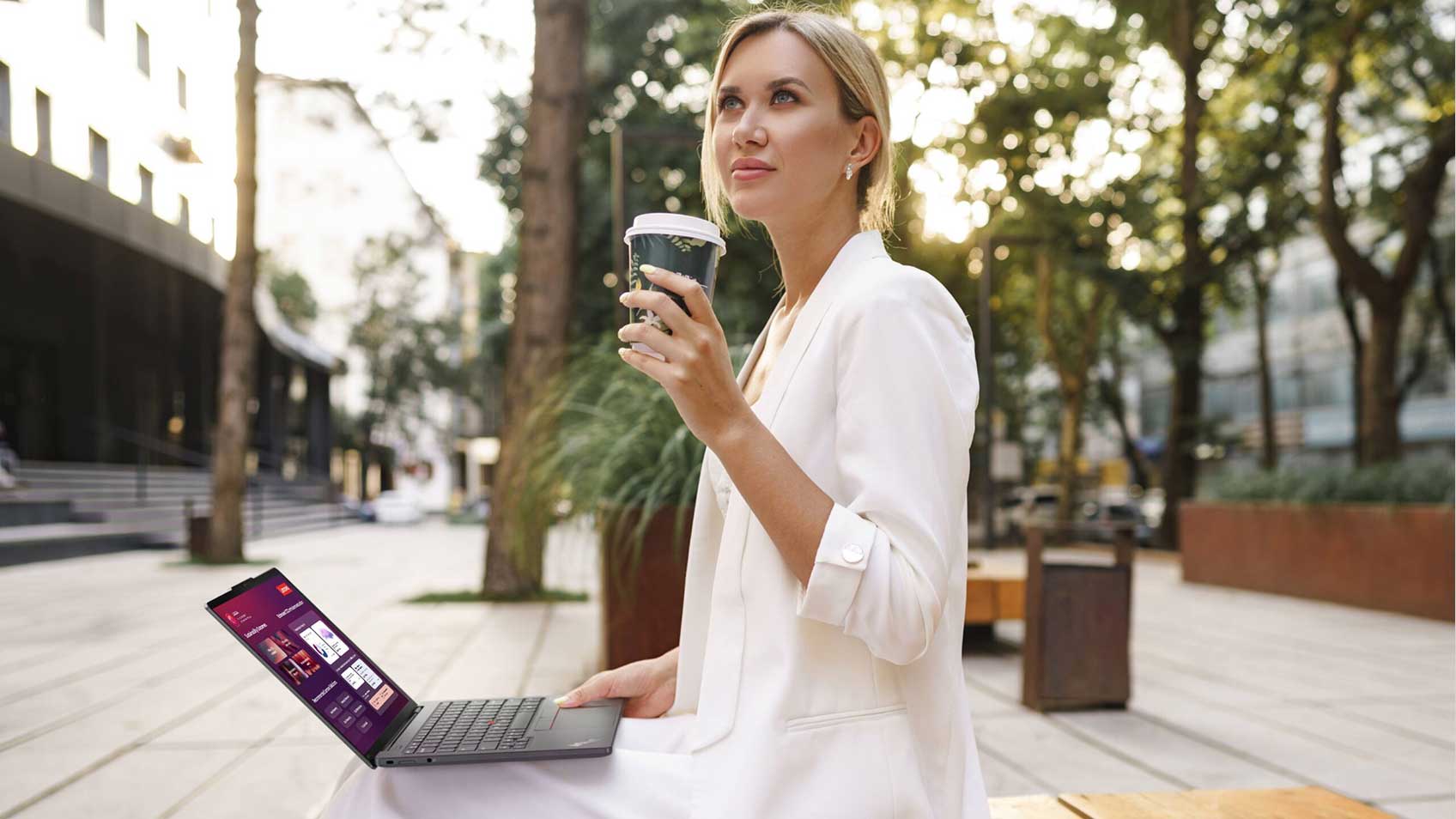 A woman sitting outside working on her laptop and enjoying a cup of coffee