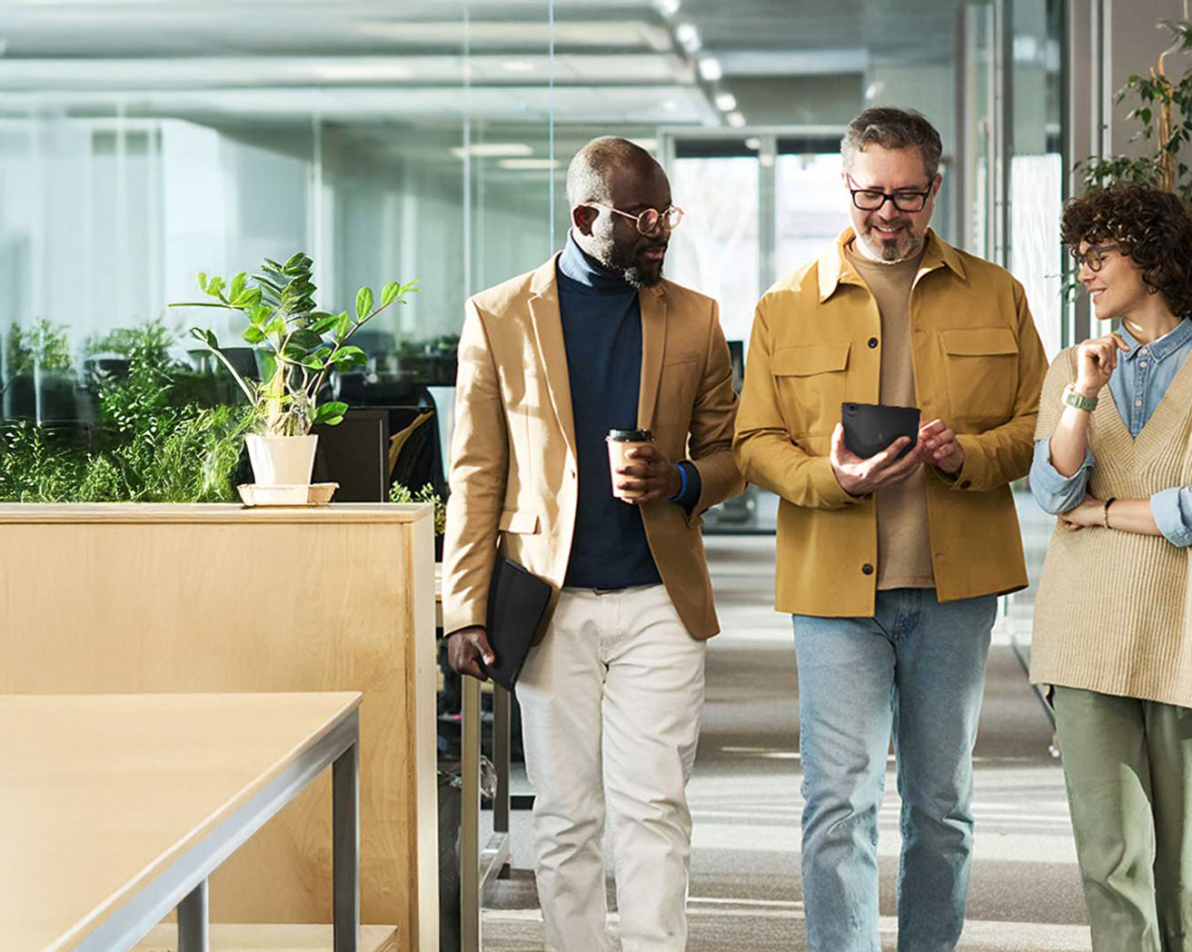 A group of colleagues walking together in a bright hallway while reviewing a tablet. 