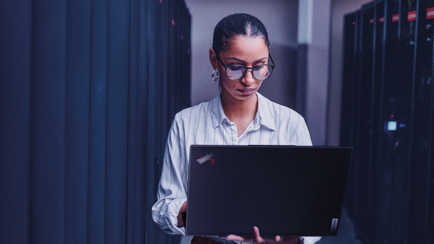 IT professional works on a Lenovo ThinkPad laptop in a server room.