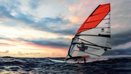 Une image d’une planche à voile avec voile rouge sur les vagues de l’océan sous un ciel coloré.