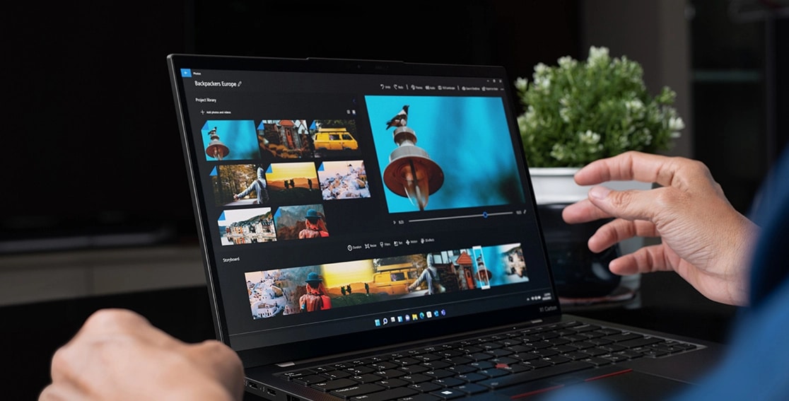 Close up of hands interacting with the Lenovo ThinkPad X1 Carbon Gen 11 laptop open, showing images & video on the display.